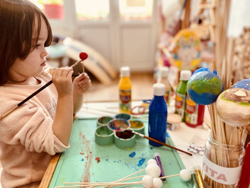 Niña de cuatro años pintando planetas. Recursos educativos de planetas