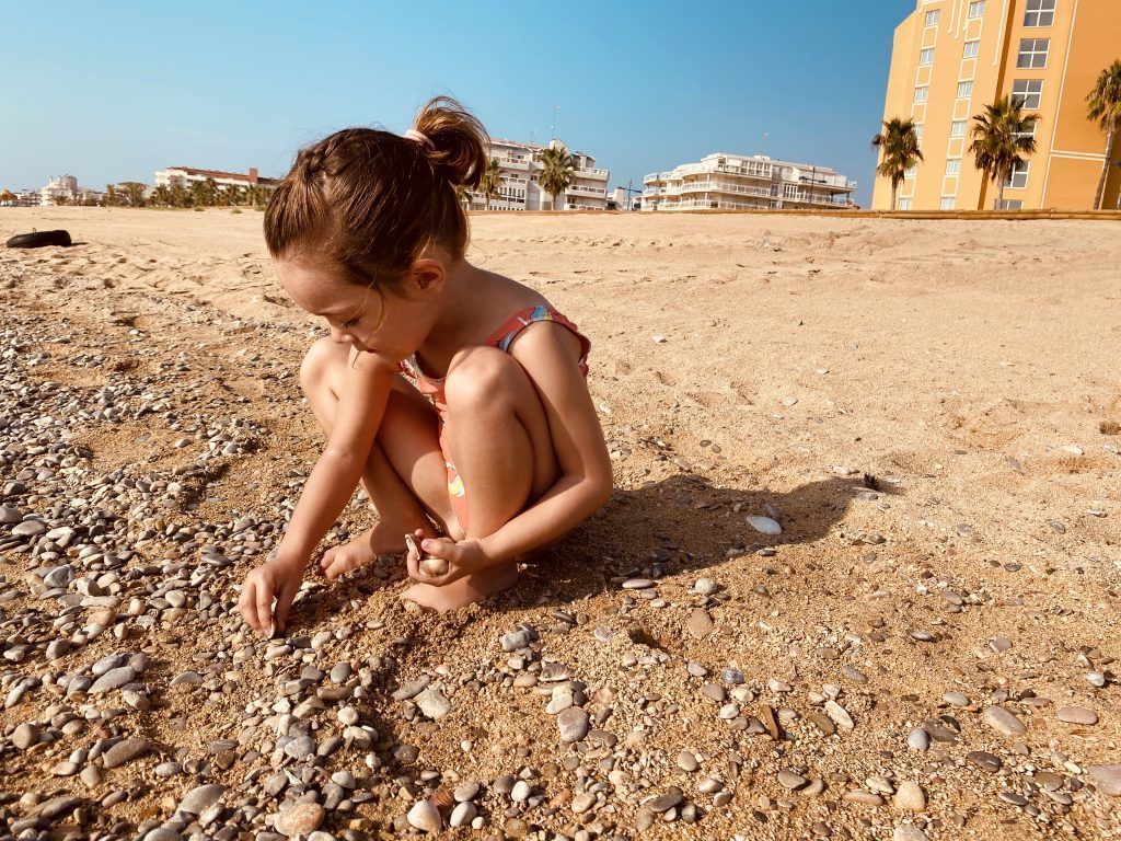niña de 4 años Buscando conchas y piedras