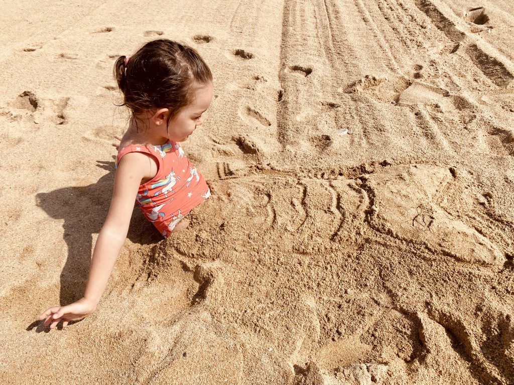 niña metida en la arena con adorno de sirena. planes con niños en peñiscola