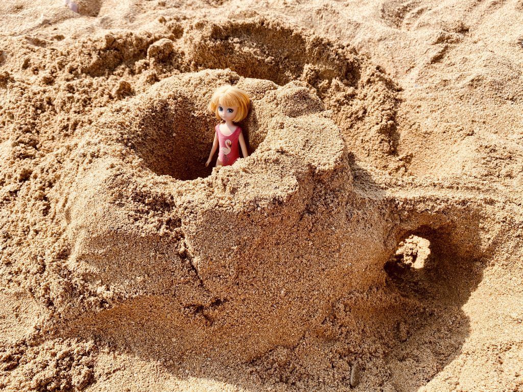 castillo de arena con muñeca en el interior