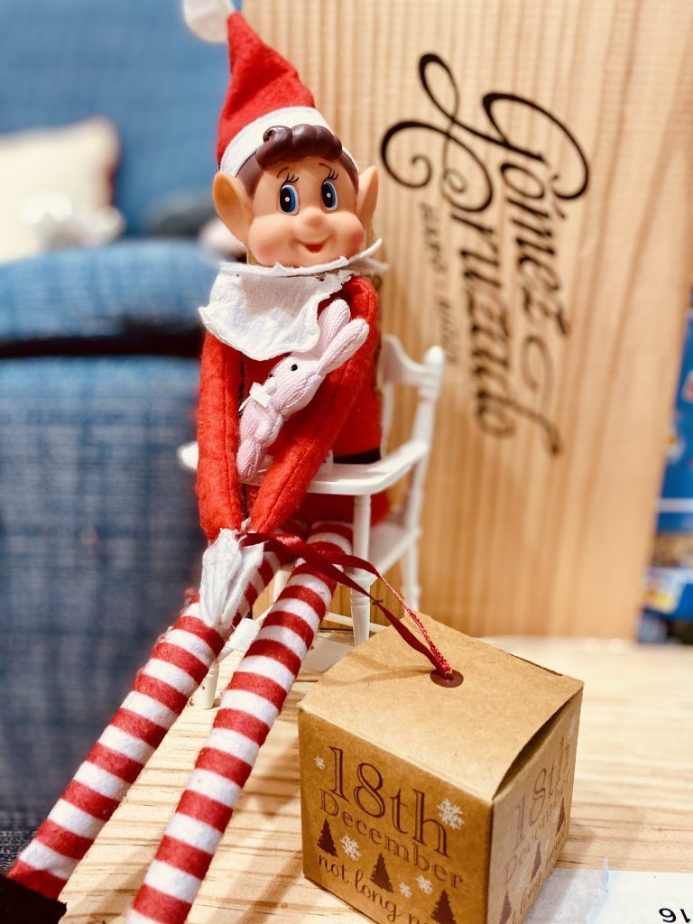 Duende travieso sujetando una cajita de regalo del calendario de adviento