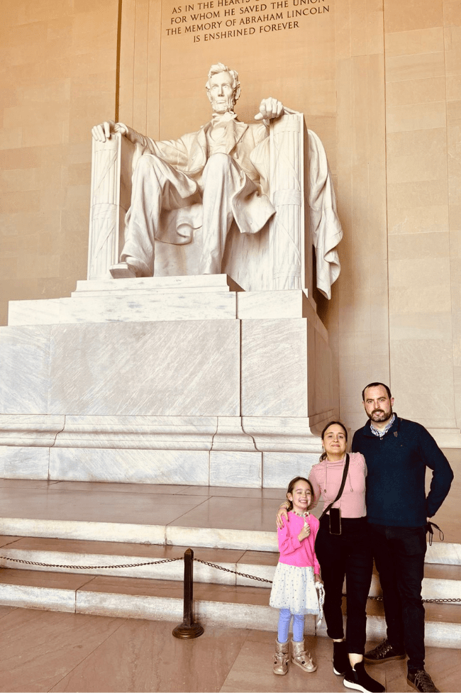 madre, padre e hija posando frente a la estatua de Lincoln que hacer en Washington dc