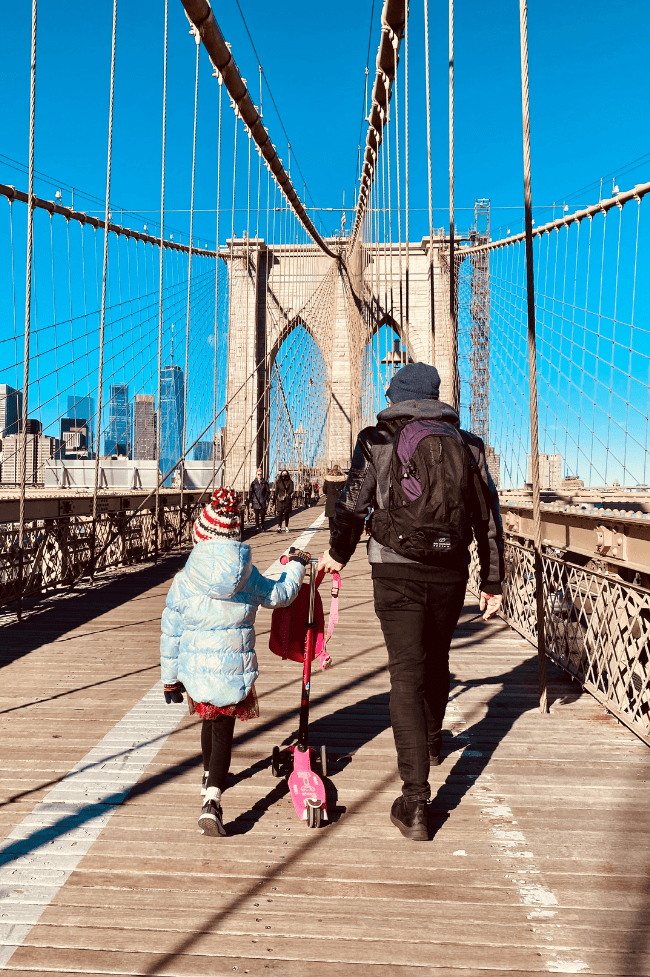 padre e hija paseando por el puente de bROOKLYN