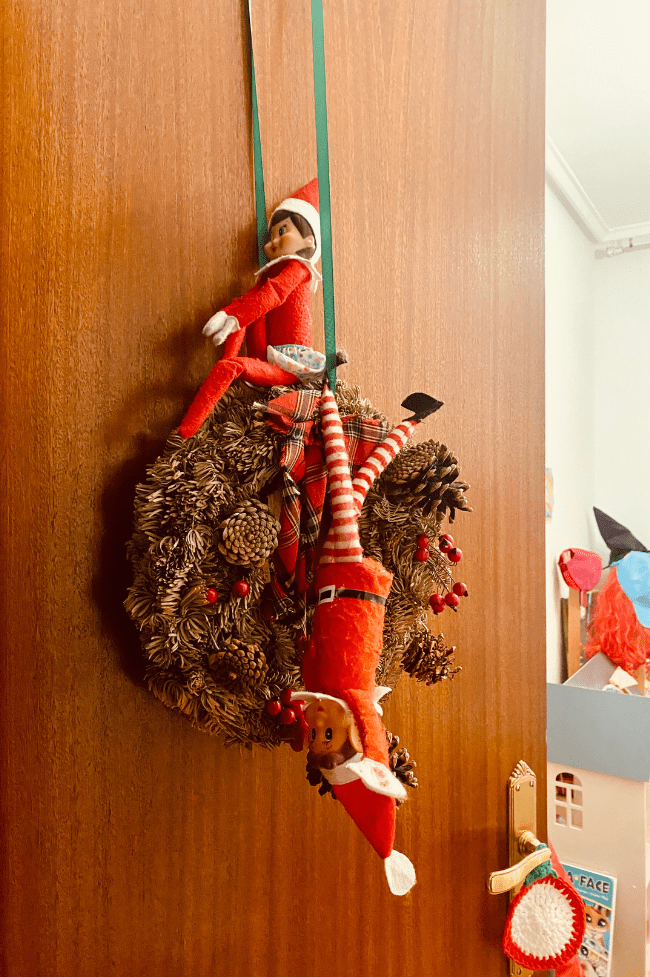 Dos elfos colgados en una corona de navidad