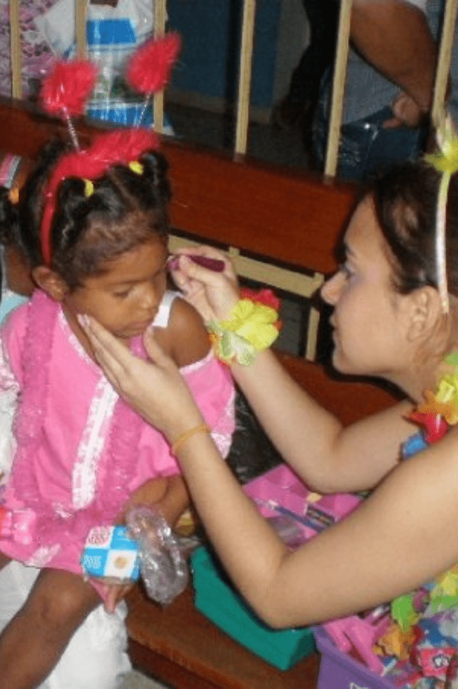 Mujer joven pintando la cara a niña en el hospital