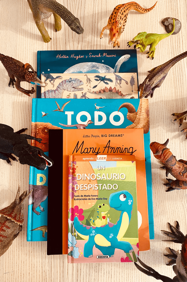 Libros de dinosaurio en fila rodeados de dinosaurios