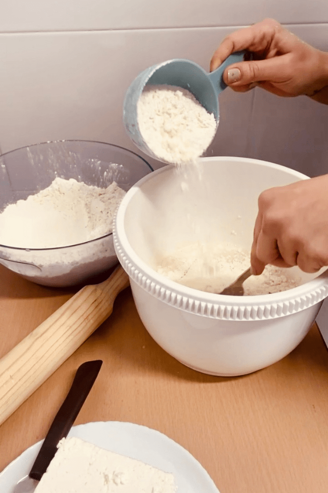 Mano de mujer añadiendo harina a la masa de tequeños