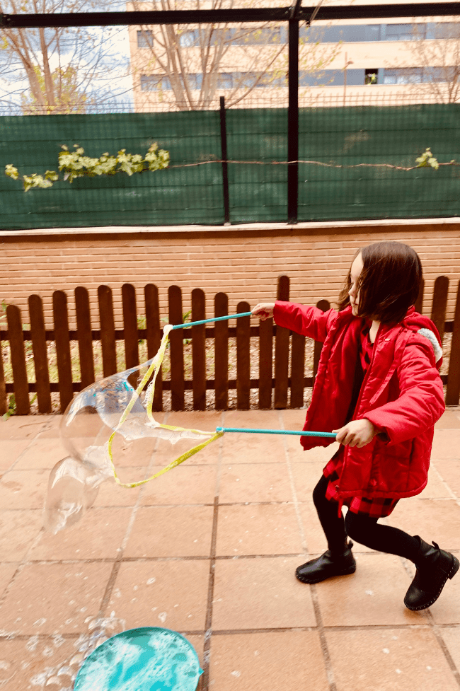 niña jugando con pompas gigantes. actividades de primavera