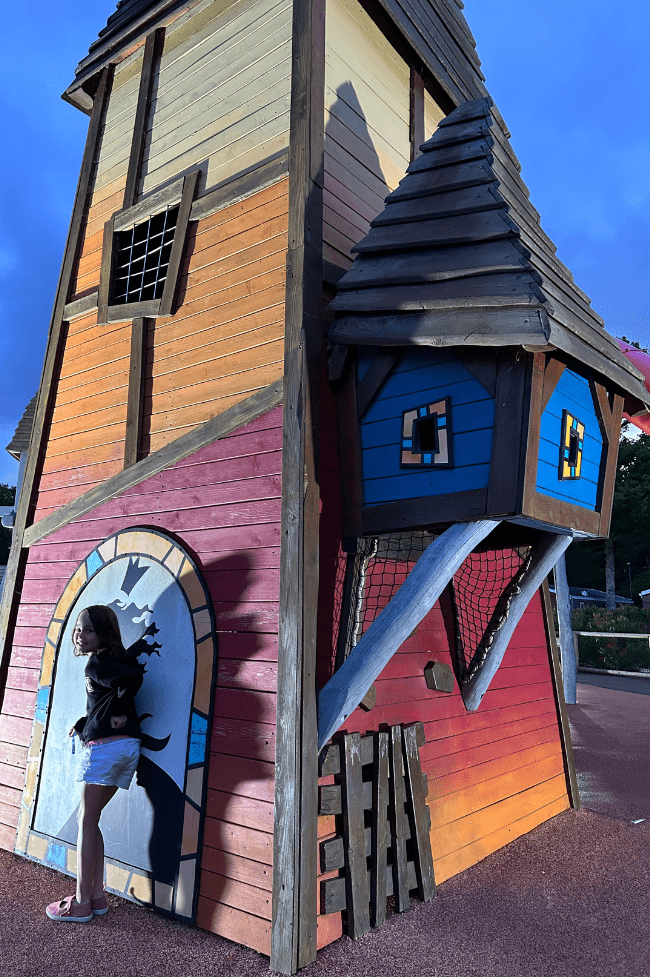 Camping en Francia con parques. Niña de seis años jugando en casita de madera